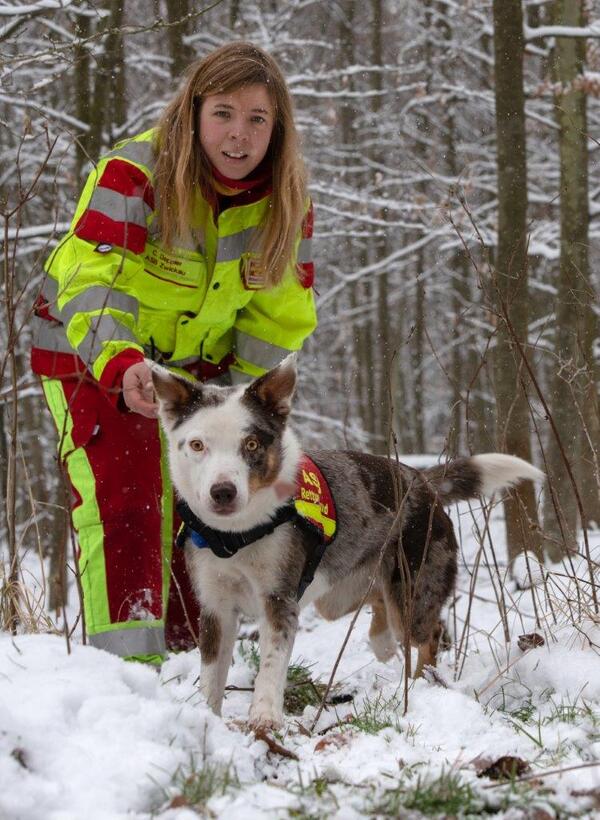 Bild vergrößern: Auf dem Bild sieht man Carola Deppler mit einem ihrer Rettungshunde beim Training im Winterwald