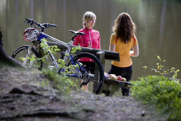 Bild vergrößern: Zwei Radfahrerinnen machen Pause an einer Bank