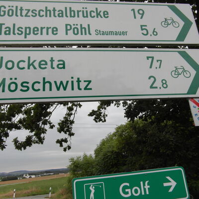 Bild vergrößern: Zwei Radwegweiser und ein Wegweiser wo es zum Golfplatz geht