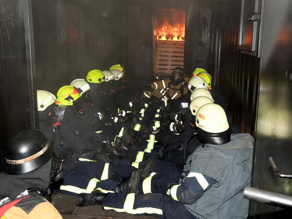 Bild vergrößern: Heißausbildung bei der Feuerwehr. Einsatzkräfte im Feuercontainer.