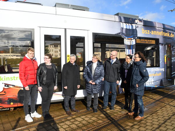 Bild vergrößern: Landrat Rolf Keil (3.von links) vor der neugestalteten Straßenbahn im Gespräch mit Studenten und weiteren Projekt-Beteiligten.