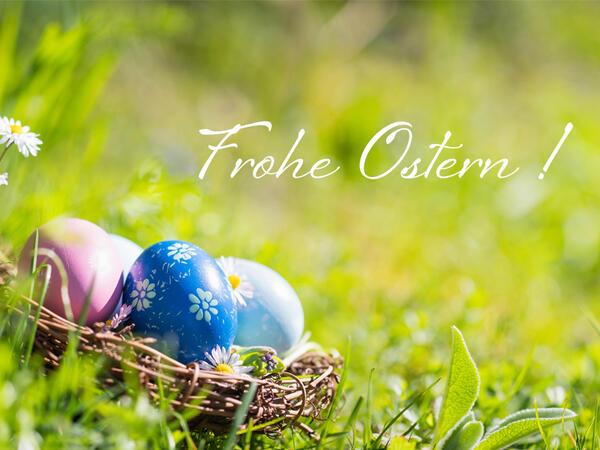 Bild vergrößern: Auf dem Bild ist ein Ostereiernest im Gras zu sehen mit dem Gruß "Frohe Ostern"