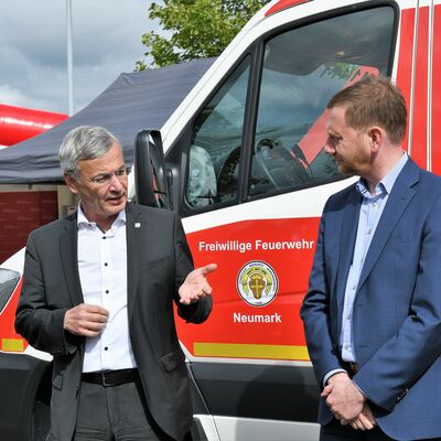 Bild vergrößern: Landrat Rolf Keil und Ministerpräsident Michael Kretschmer stehen vor einem Feuerwehrauto der freiwilligen Feuerwehr und unterhalten sich.