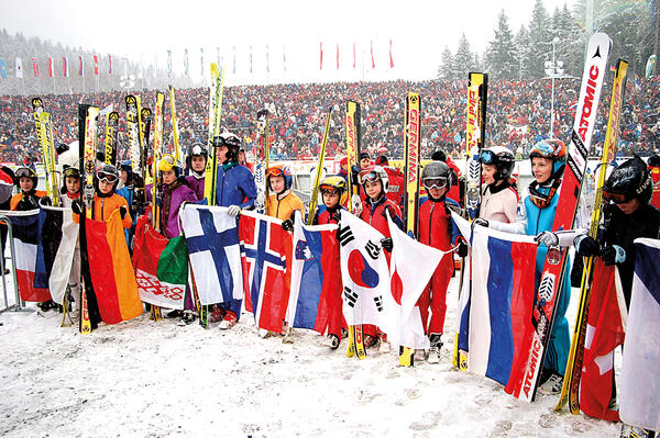 Bild vergrößern: Das Bild zeigt die Teinehmer eines Weltcups zum Skispringen in der Vogtland Arena Klingenthal aus verschiedenen Ländern mit ihren Landesflaggen.