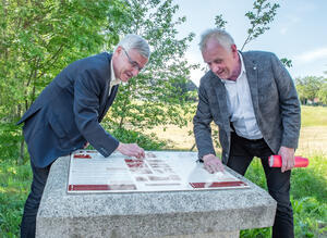 Bild vergrößern: Landrat Rolf Keil und der Europaabgeordnete Dr. Peter Jahr putzen die Tafel am Gedenkstein für Französische Kriegsgefangene in Irfersgrün