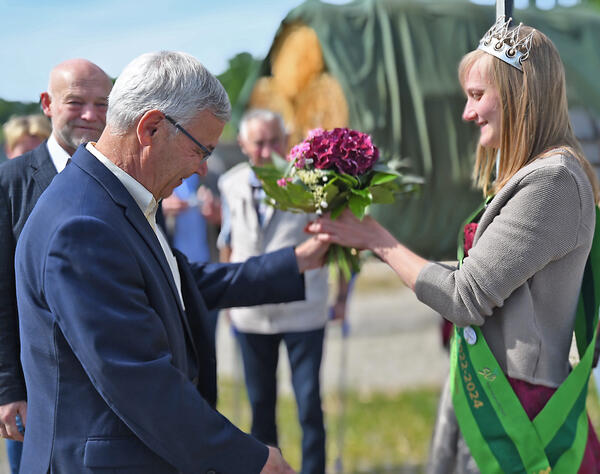 Landrat Rolf Keil gratuliert der neuen sächsischen Milchkönigin Sandra Hartenstein und überreicht ihr einen Blumenstrauß.