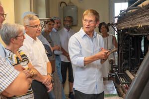 Bild vergrößern: Dr. Frank Luft vom Spitzenmuseum erklärt die Wirkungseise einer Spitzenstickerei-Maschine.