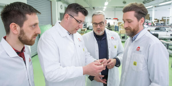 Landrat Thomas Hennig besucht die Produktionsst&auml;tte von IK elektronik in Muldenhammer. IK-Gesch&auml;ftsf&uuml;hrer und Inhaber Jan-Erik Kunze (3.v.l.) sowie Jan Seidel, Leiter der Prozessentwicklung (r.) und Marcel Polster, Leiter Produktion (l.) machen den Landrat mit Erzeugnissen aus der laufenden Produktion vertraut.