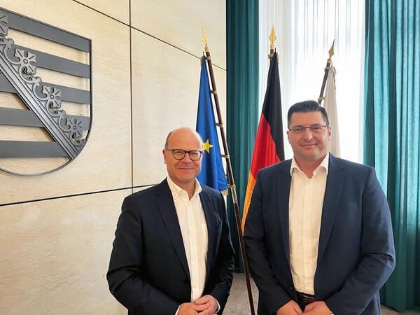 Auf dem Bild sieht man Landrat Thomas Hennig (rechts) zu Besuch beim Chef der Sächsischen Staatskanzlei, Oliver Schenk (links).