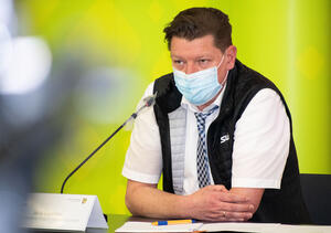 Bild vergrößern: Das Bild zeigt Jens Leistner, den Geschäftsführer des Rettungszweckverbandes Südwestsachsen am Tisch sitzend, hiner einem Mikrofon mit einer Mund-Nasen-Bedeckung.
