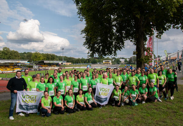 Das Bild zeigt das Laufteam des Vogtlandkreises, erkennbar an den grünen T-Shirts. Im Hintergrund ist das Vogtlandstadion zu sehen.