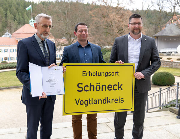 Bild vergr&ouml;&szlig;ern: Drei Leute halten ein Schild.