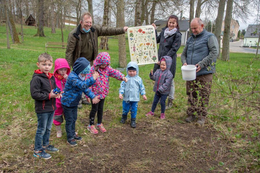 Bild vergrößern: Auf dem Bild sieht man Mitarbeiterinnen und Mitarbeiter des Natur- und Umweltzentrums Vogtland, wie sie gemeinsam mit den Kindern ein Plakat über Wildblumen betrachten.