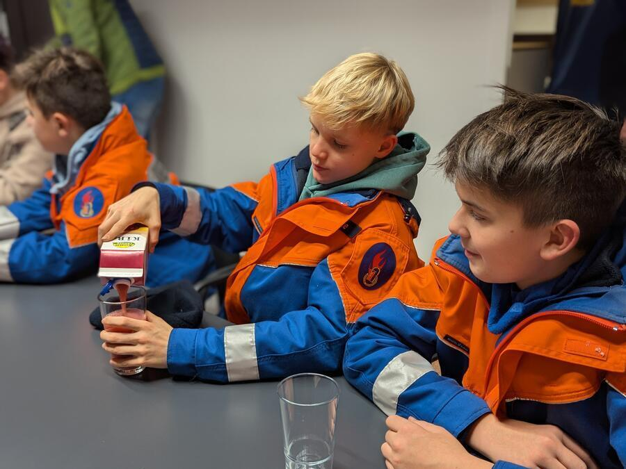 Zwei Jungen gie&szlig;en sich Saft ein.