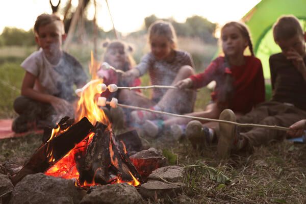 Auf dem Bild sieht man Kinder, welche an einem Lagerfeuer sitzen.