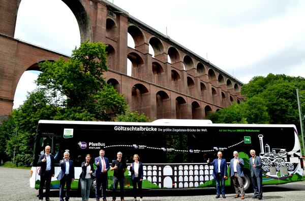 Das Bild zeigt im Hintergrund die Göltzschtalbrücke. Im Vordergrund steht der neue Bus mit Lokal-, Regional- und Bundespolitikern.