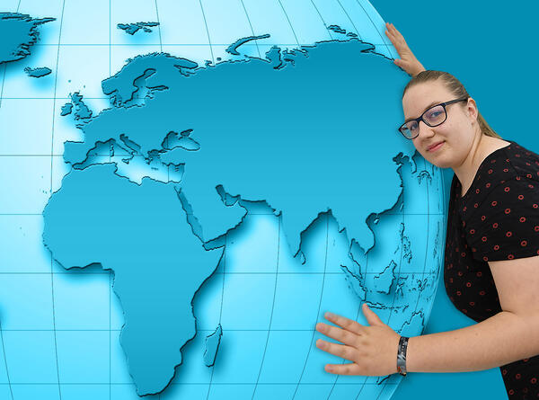 Bild vergrößern: Auf dem Bild ist die Auszubildende Annika Ruß zu sehen, die eine Weltkugel umarmt.