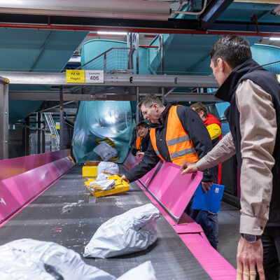 Bild vergr&ouml;&szlig;ern: Landrat Thomas Hennig packt an einem F&ouml;rderband im DHL-Paketzentrum Neumark mit an und sortiert Sendungen.