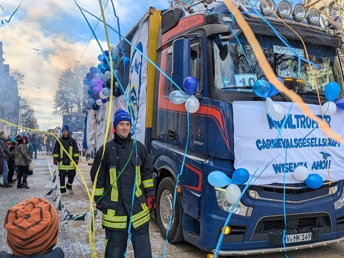Ein Lkw f&auml;hrt vorbei, um ihn herum fliegen bunte Luftschlangen.