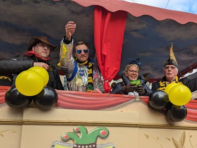 Politiker stehen auf dem Marschallwagen und werfen S&uuml;&szlig;igkeiten.