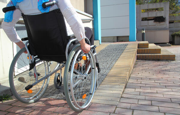 Bild vergrößern: Auf dem Bild sieht man einen Rollstuhlfahrer, der eine Rampe hinauf fährt.