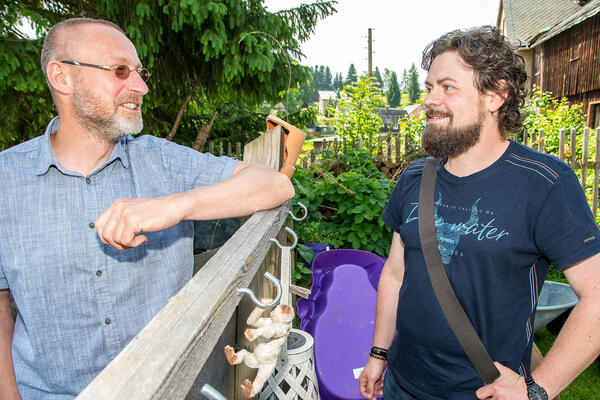 Bild vergrößern: Das Bild zeigt Pflegepapa Thomas und Robert Riedel vom Jugendamt Vogtlandkreis an einem Zaun stehend.