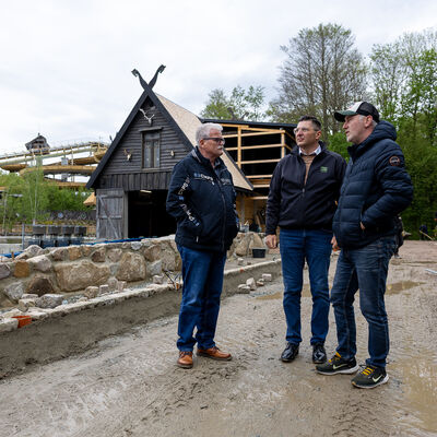 Bild vergr&ouml;&szlig;ern: Lutz M&uuml;ller, Landrat Thomas Hennig und Jan V&ouml;lkel auf der Baustelle der neuen Achterbahn &raquo;D&oslash;nnervind". Im Hintergrund das Stationsgeb&auml;ude im nordischen Stil.