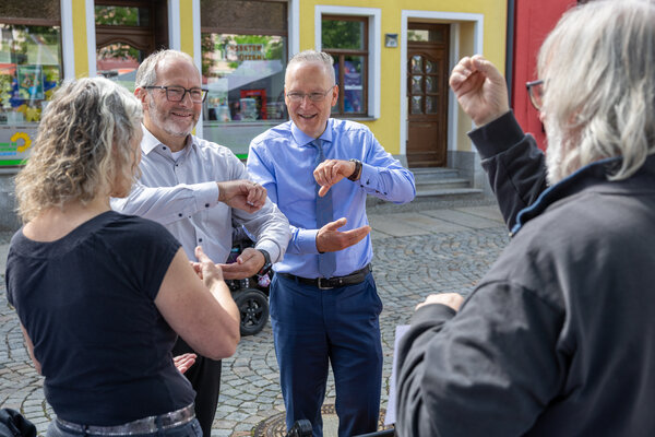 Bild vergr&ouml;&szlig;ern: Beigeordneter Dr. Axel Steinbach und Oberb&uuml;rgermeister Jens Scharff kamen beim Auerbacher Familientag mit der Geb&auml;rdensprache in Kontakt und probierten einzelne Zeichen selbst aus.
