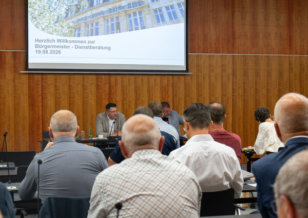 Bild vergr&ouml;&szlig;ern: Das Bild zeigt Landrat Thomas Hennig vor einer Leinwand. Vor ihm sitzen mehrere Menschen.