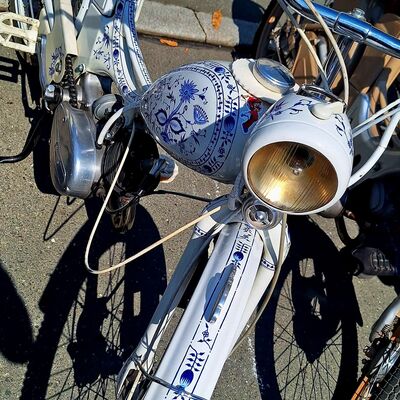 Das Bild zeigt ein helles Moped mit Verzierungen.