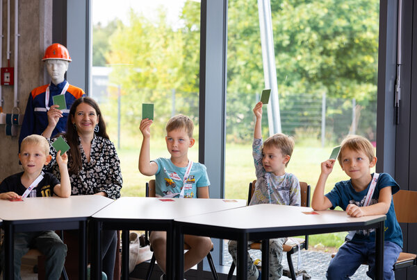 Bild vergr&ouml;&szlig;ern: Das Bild zeigt die Kinder und Erzieherin des Kinderland Pausa. Sie halten gr&uuml;ne Karten hoch.