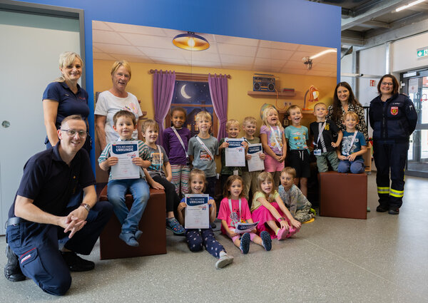 Bild vergr&ouml;&szlig;ern: Die Kinder des Kinderland Pausa waren die ersten, die das neue Modul am FloBIZ absolviert haben. Auf dem Bild sitzen sie vor einem Bild eines Kinderzimmers.