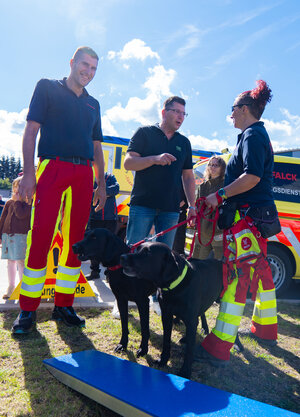 Bild vergr&ouml;&szlig;ern: Das Bild zeigt Landrat Thomas Hennig mit zwei Rettungshunden von Falck. Diese werden f&uuml;r die Personensuche eingesetzt.
