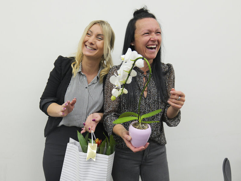 Zwei Frauen halten Geschenke und lachen.