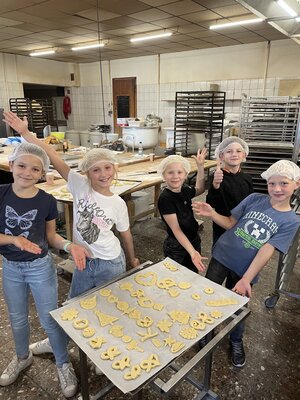 Bild vergr&ouml;&szlig;ern: Das Bild zeigt die Kinder vor einem Backblech in einer B&auml;ckerei.