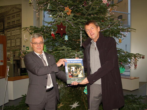 Bild vergrößern: Verleger Hartmut Briese (rechts) übergibt das erste druckfrische Exemplar an Landrat Rolf Keil.