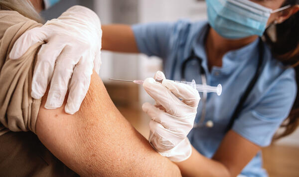 Bild vergrößern: Das Bild zeigt eine Krankenschwester, die eine Spritze aufgezogen hat und im Begriff ist, mit dieser eine Impfung zu geben.